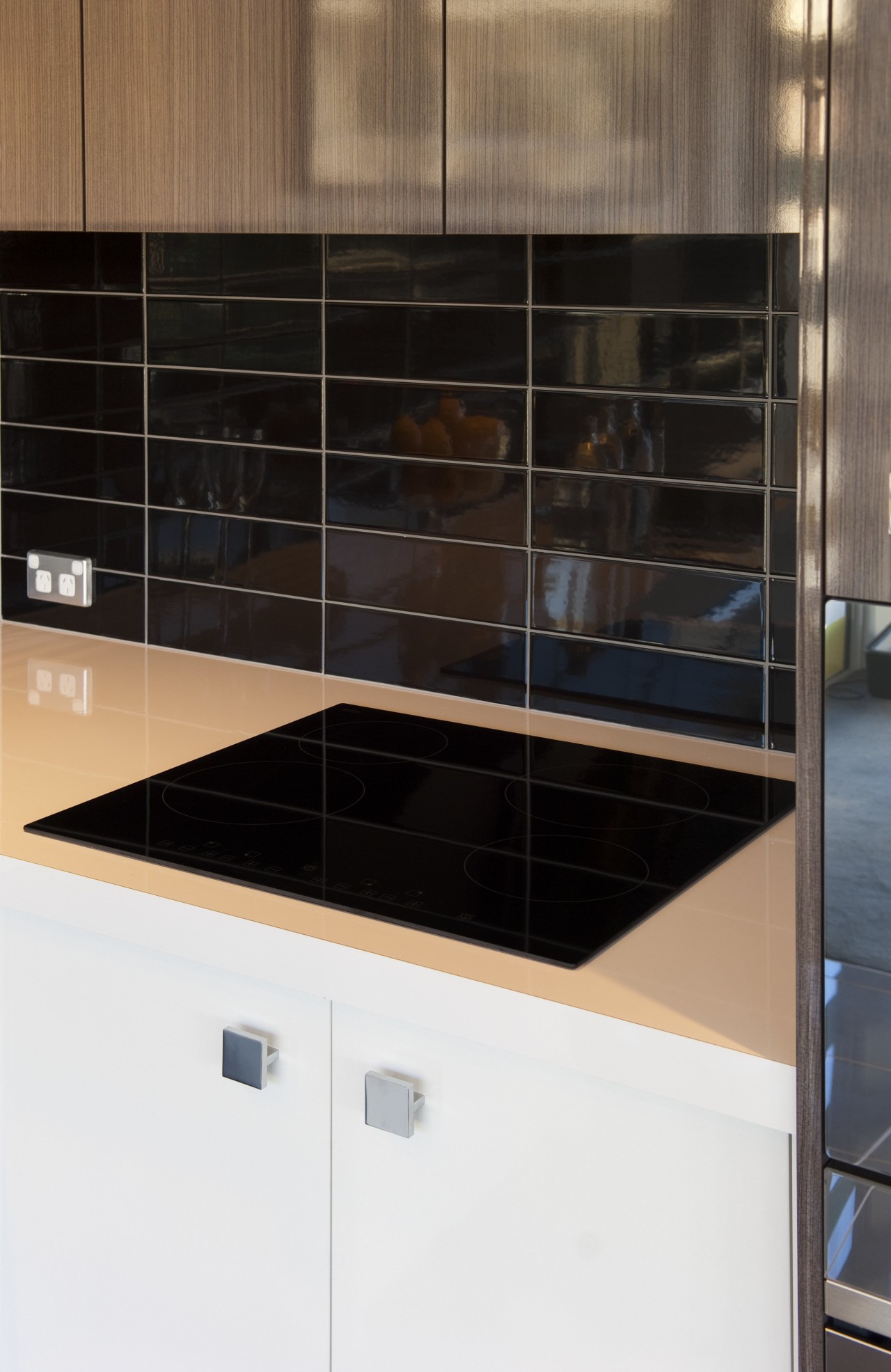 Black cooktop on white bench with black splashback. cabinetry, countertop, glass, kitchen, product design, black, white