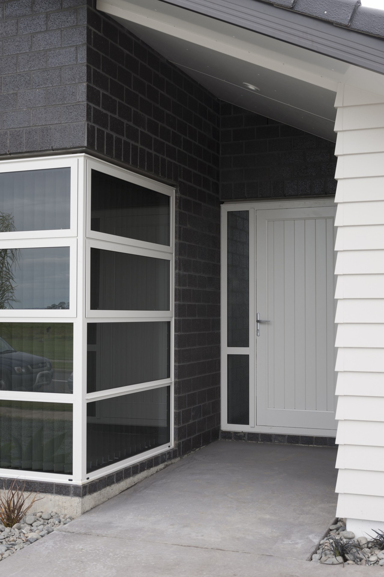 Exterior of single-storey house, dark stone cladding, and building, door, facade, home, house, siding, window, gray, black