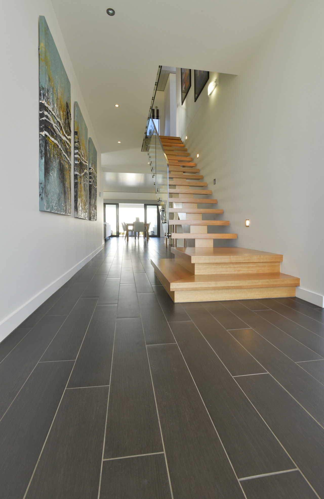 this new home features continuous timber look porcelain daylighting, floor, flooring, handrail, hardwood, interior design, laminate flooring, stairs, tile, wood, wood flooring, gray