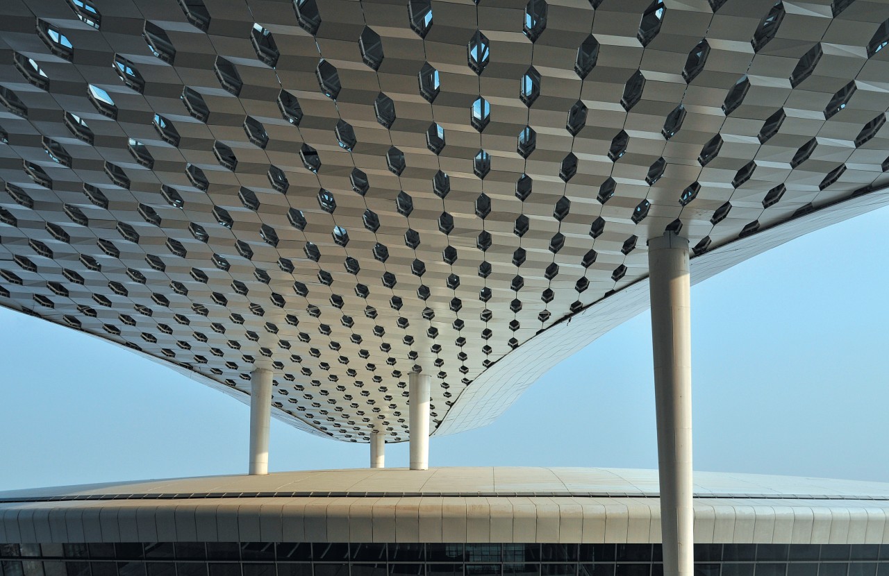 :The terminal features white conical support columns that architecture, building, ceiling, daylighting, infrastructure, line, roof, sky, structure, gray, black