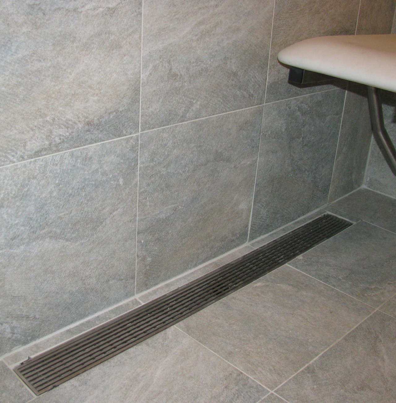 Luxe Linear Drain with a decorative steel grate. floor, flooring, plumbing fixture, tile, gray