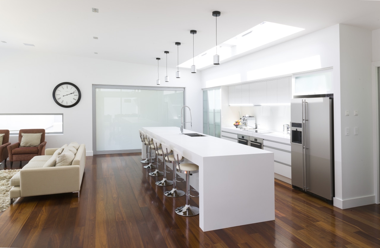 Contemporary white kitchen with large island. Internal sliding floor, flooring, interior design, interior designer, kitchen, living room, real estate, wood flooring, white