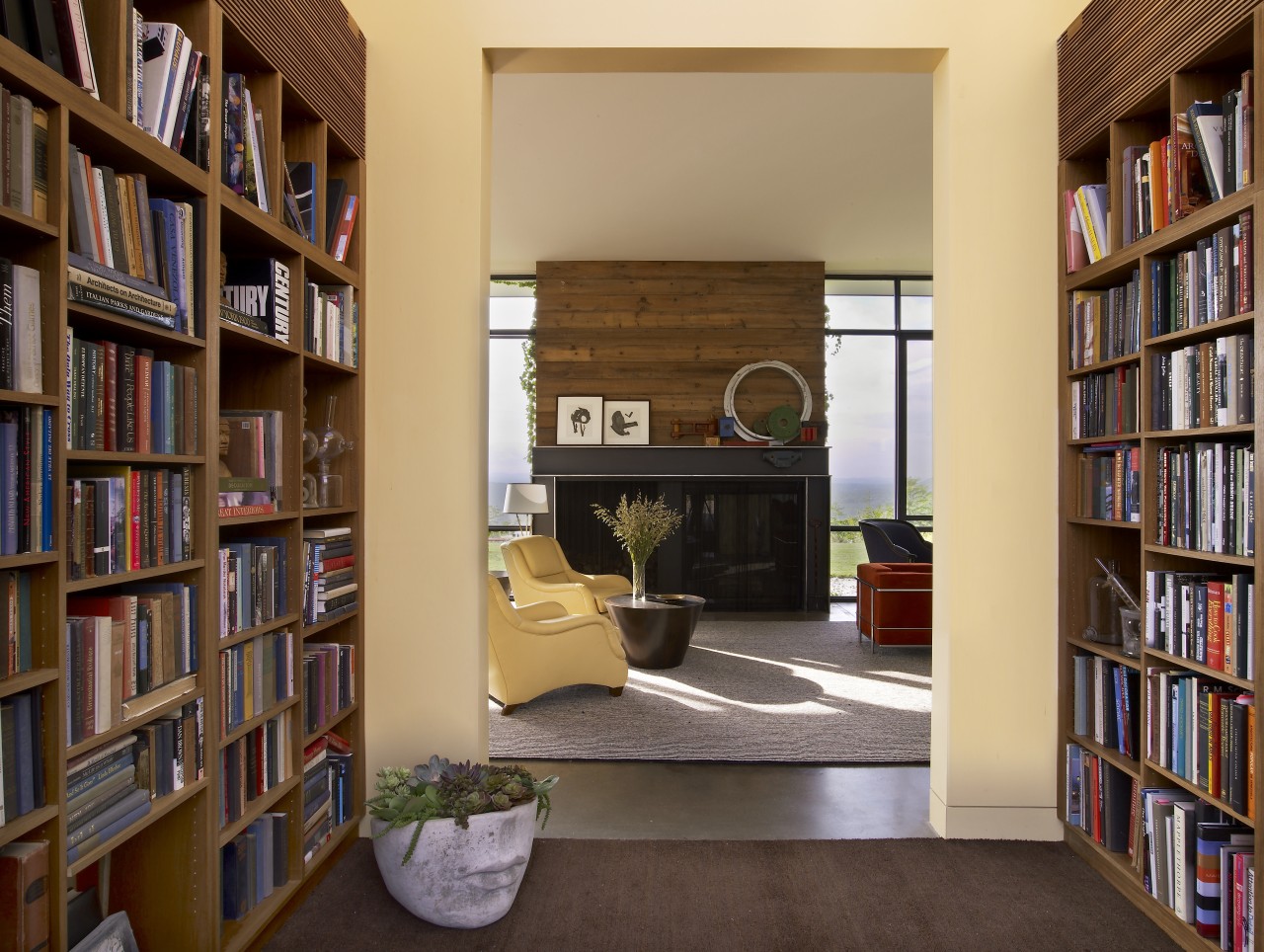 With bookshelves lining both sides, the entry to bookcase, bookselling, furniture, institution, interior design, library, library science, living room, public library, shelf, shelving, orange