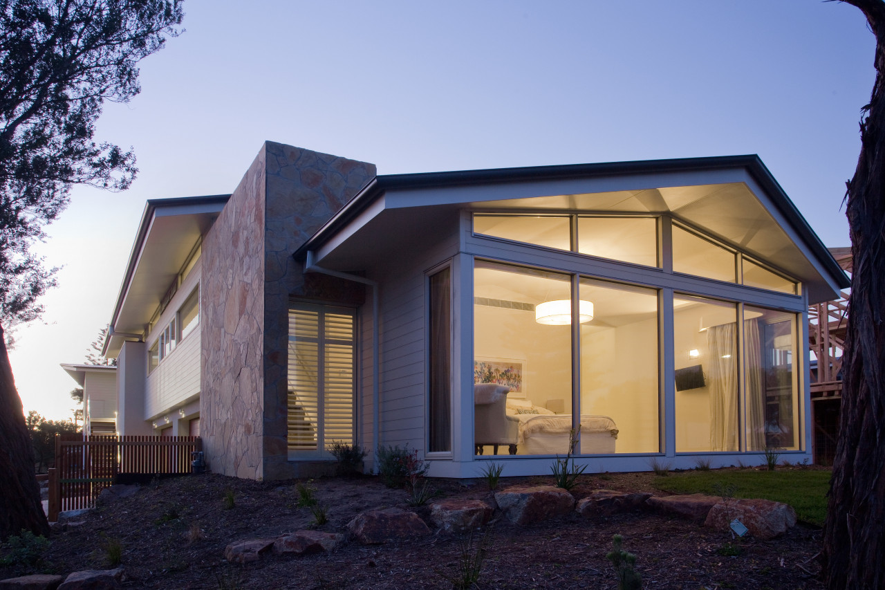 The mid-level master bedroom designed by Graeme Alexander architecture, building, cottage, elevation, facade, home, house, lighting, property, real estate, residential area, roof, siding, window, teal