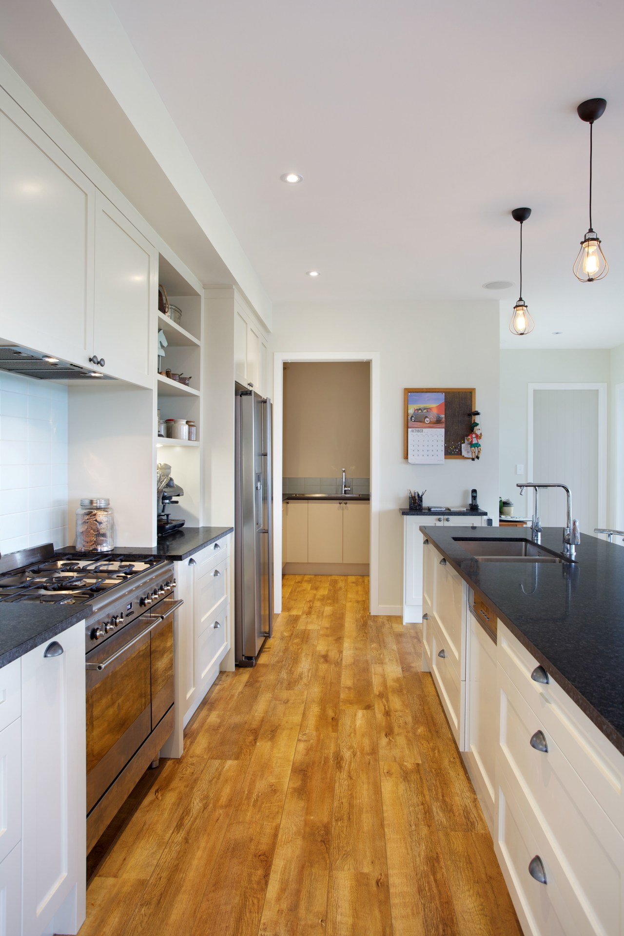 This galley kitchen features Shaker-style cabinets and honed cabinetry, countertop, cuisine classique, floor, flooring, hardwood, interior design, kitchen, laminate flooring, real estate, room, wood, wood flooring, gray