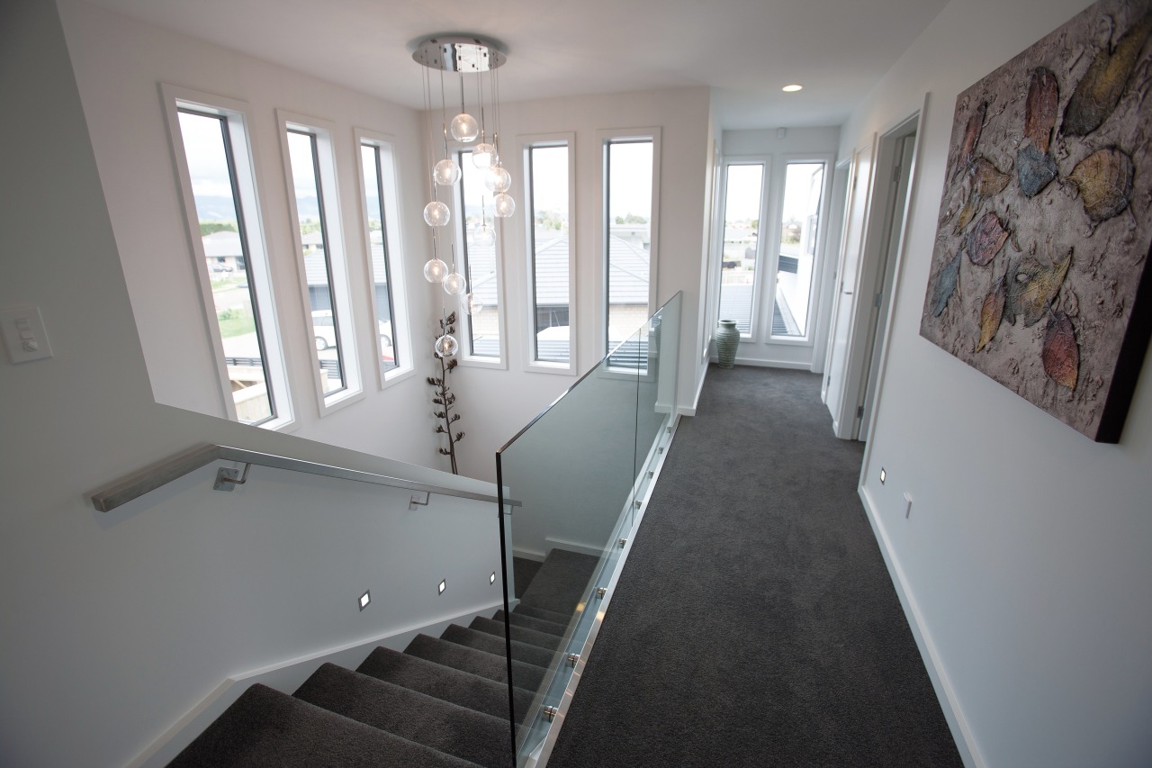 A double-height atrium brings light into the stairwell architecture, ceiling, daylighting, estate, floor, flooring, handrail, home, house, interior design, property, real estate, room, stairs, wall, window, wood, gray