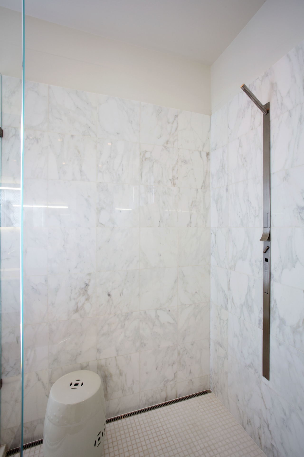 This shower stall has a Carrara marble lining bathroom, ceiling, floor, flooring, interior design, plaster, plumbing fixture, room, tile, wall, gray