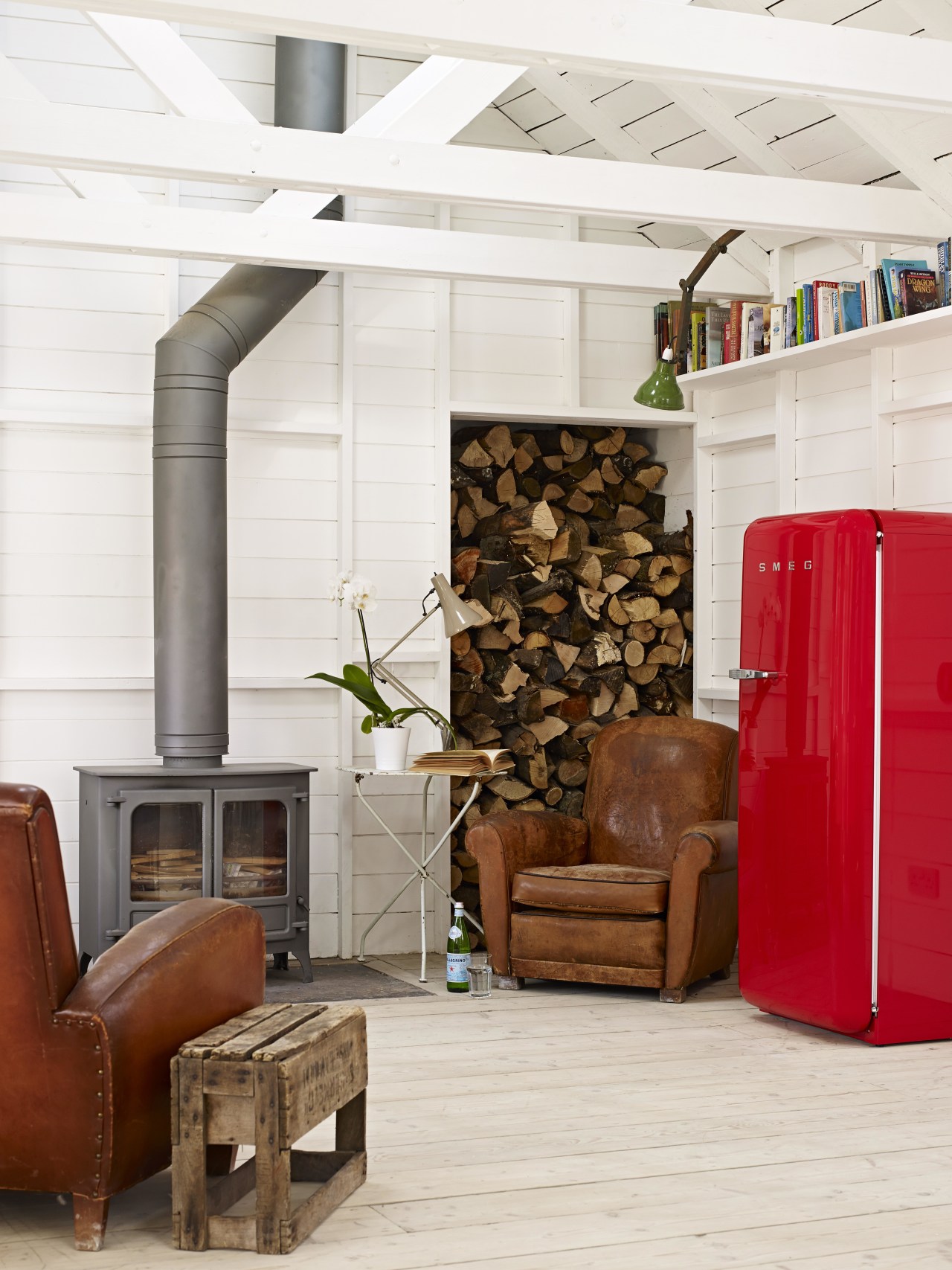 A bright red Smeg FAB28 refrigerator is the chair, floor, flooring, furniture, home, interior design, living room, loft, white