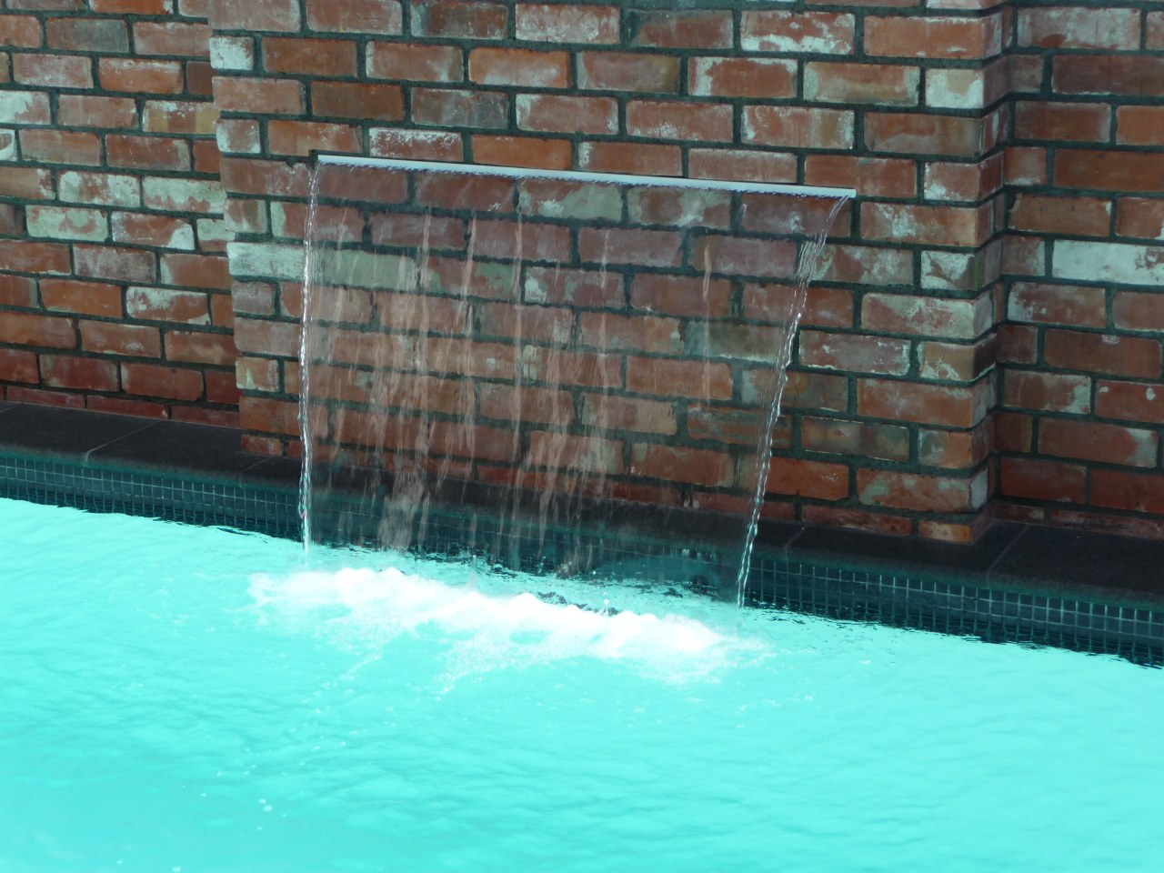 This Mayfair pool includes a 1200mm-wide water feature. brick, swimming pool, wall, water, water feature, teal, black