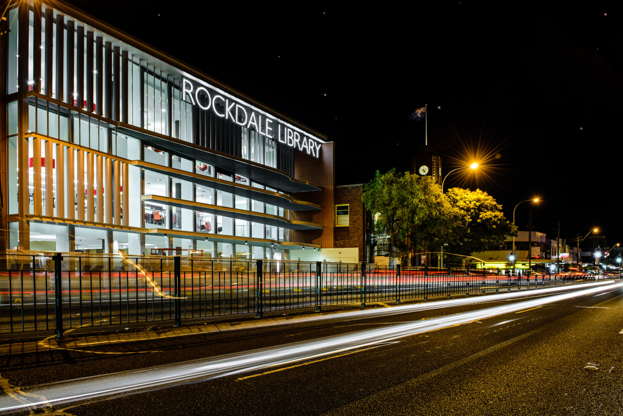 :Located next to the 1940s Rockdale Town Hall, architecture, building, car, city, cityscape, downtown, evening, house, infrastructure, light, lighting, metropolis, metropolitan area, mixed use, night, residential area, road, sky, street, street light, structure, town, urban area, black