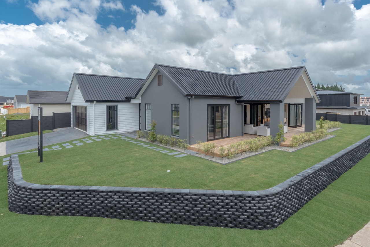 This twin-gabled, two-tone showhome by Landmark Homes  area, cottage, elevation, estate, facade, grass, home, house, land lot, landscape, lawn, property, real estate, residential area, roof, siding, suburb, yard, gray, green