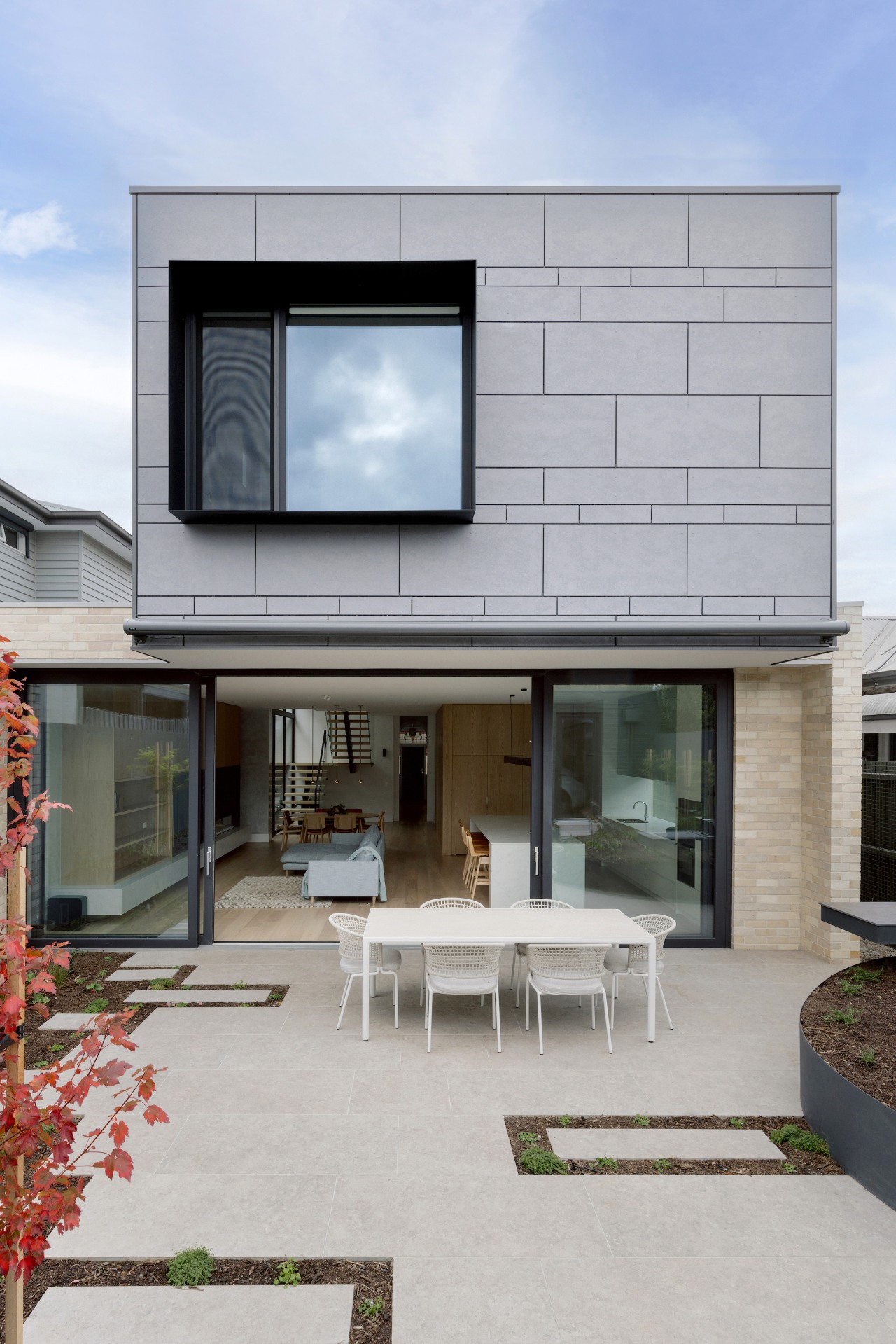 The rear façade features cement-sheet cladding with semi-random 