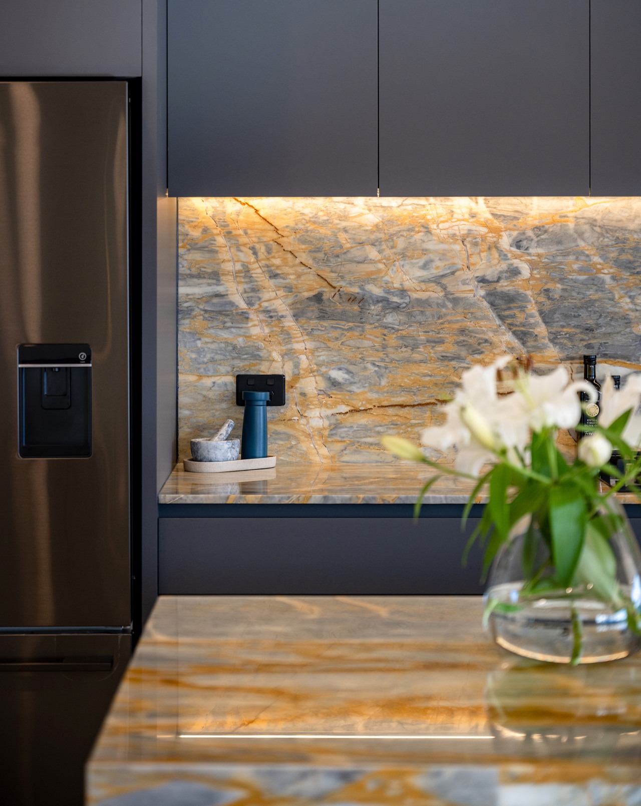 The stone benchtop and splashback give the kitchen 