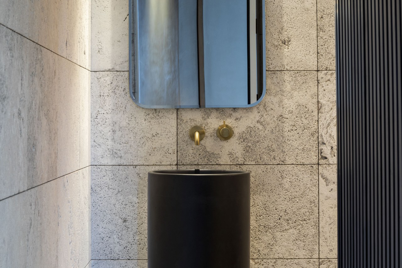 Brushed brass wall tapware sits equidistant between mirror 