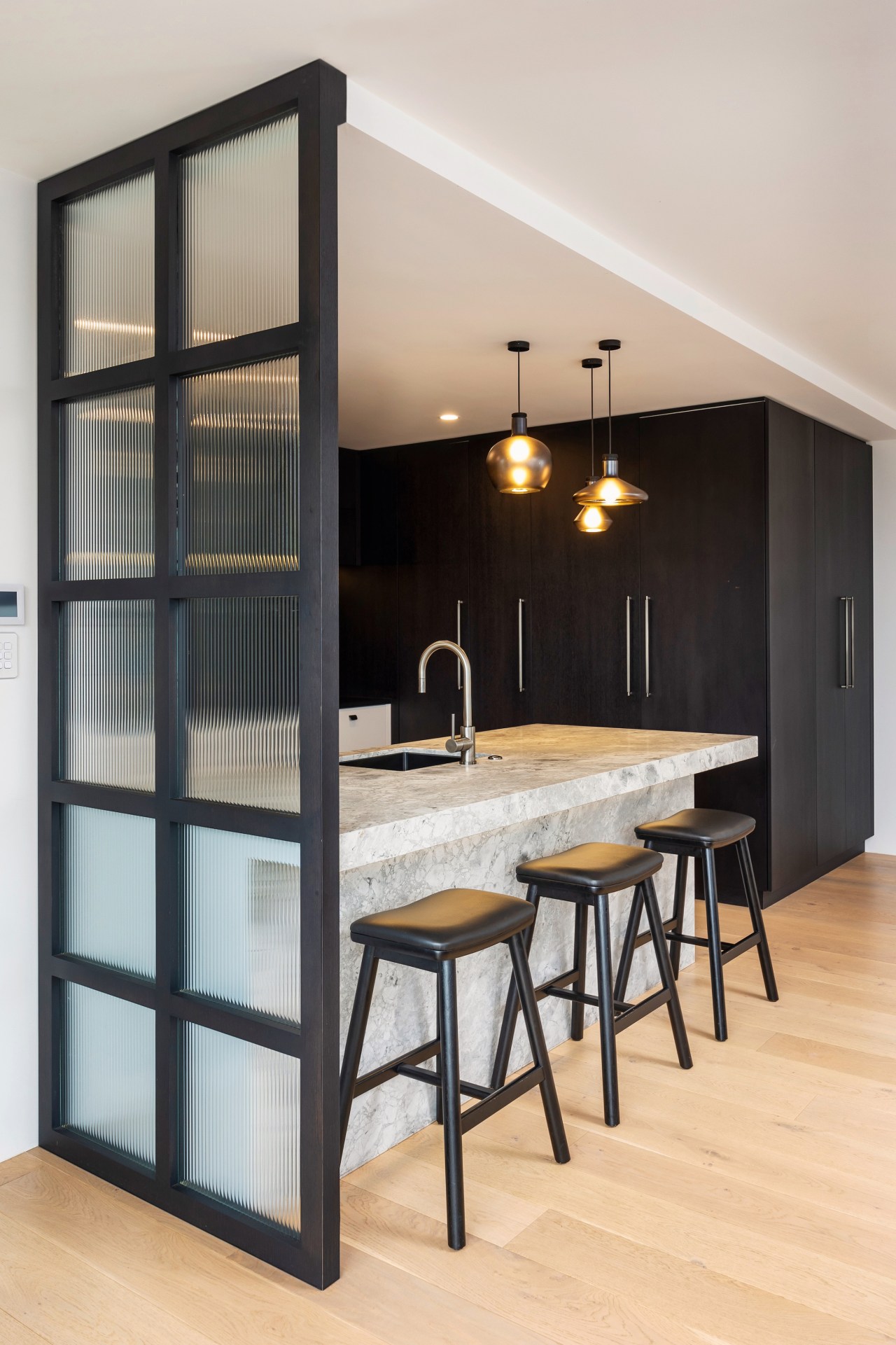 The kitchen boldly contrasts with the pale wood 