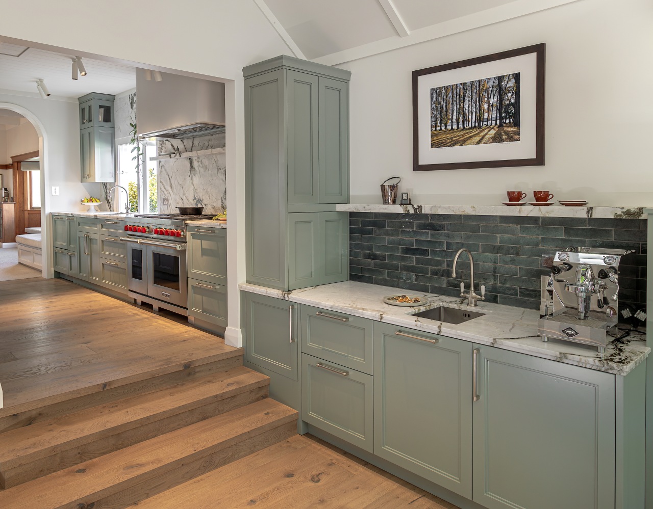 A subtle green cabinetry finish connects with the 