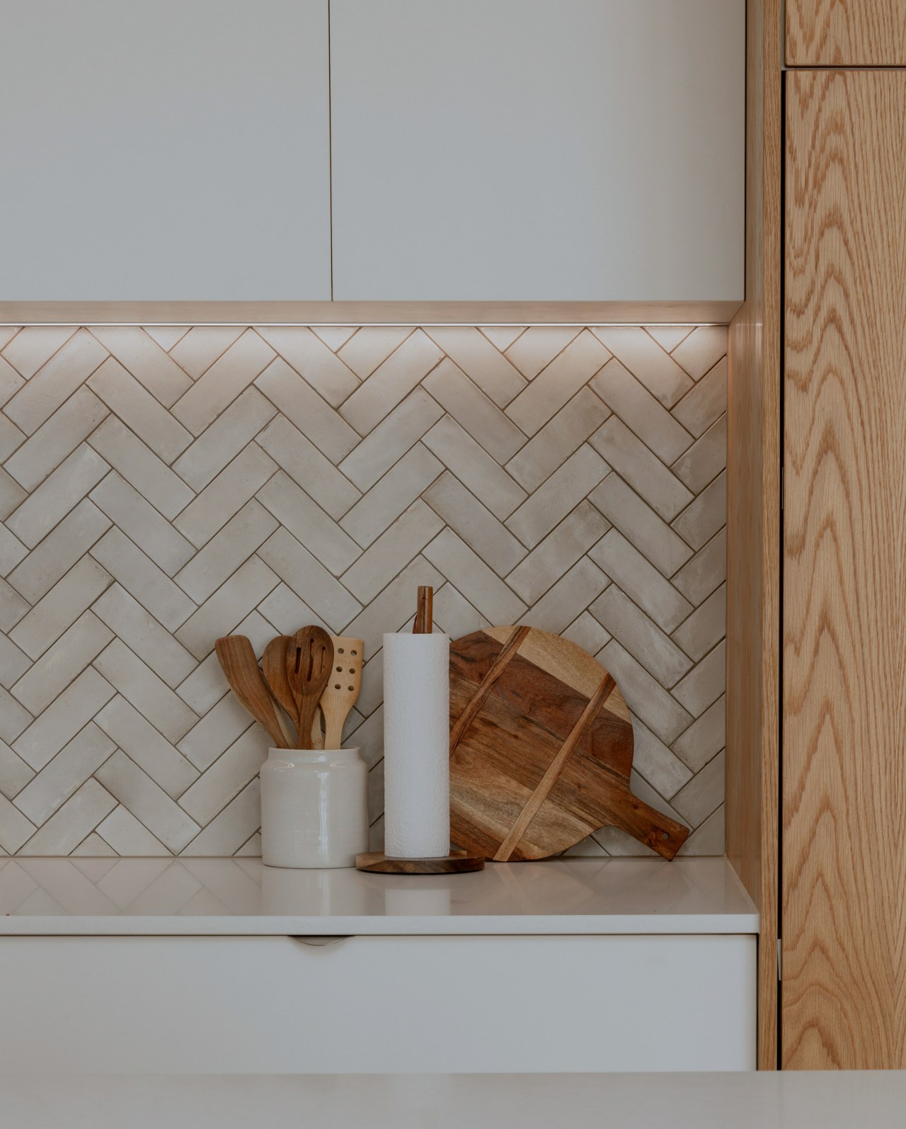A hand-laid herringbone tiled splashback adds a subtle, 