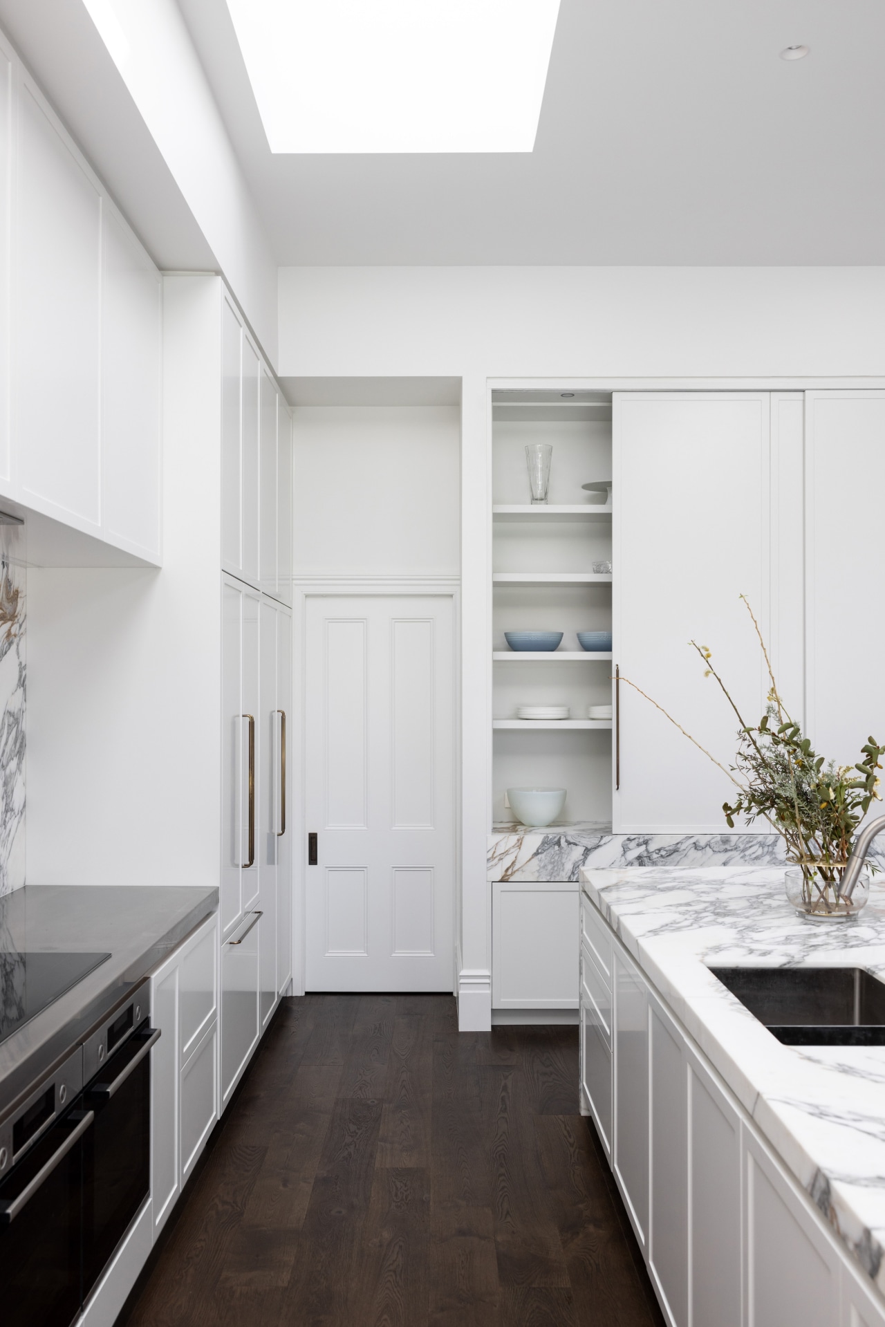 The kitchen features white cabinetry, dark floors and 