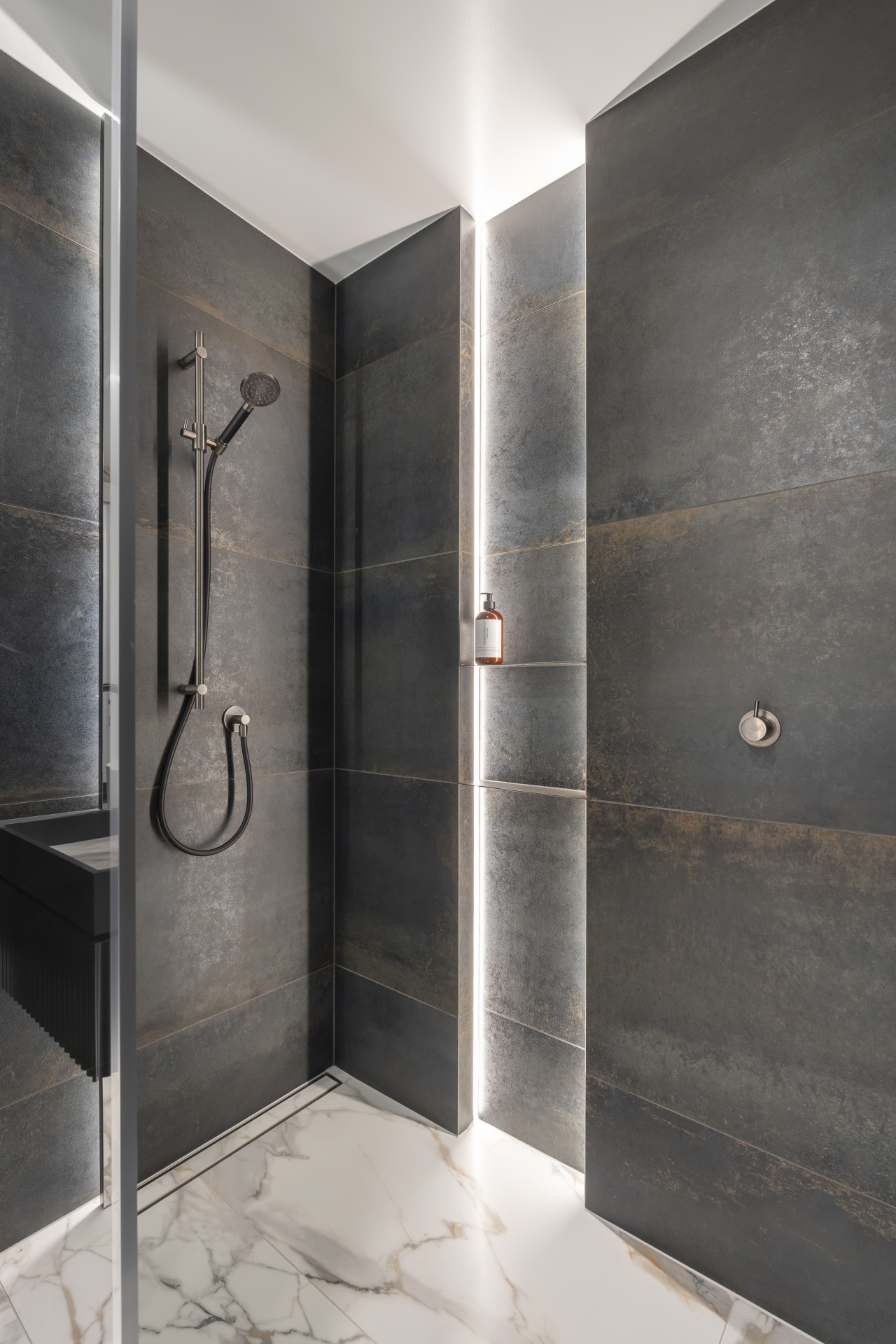 The lit shower niche echoes the display shelving 