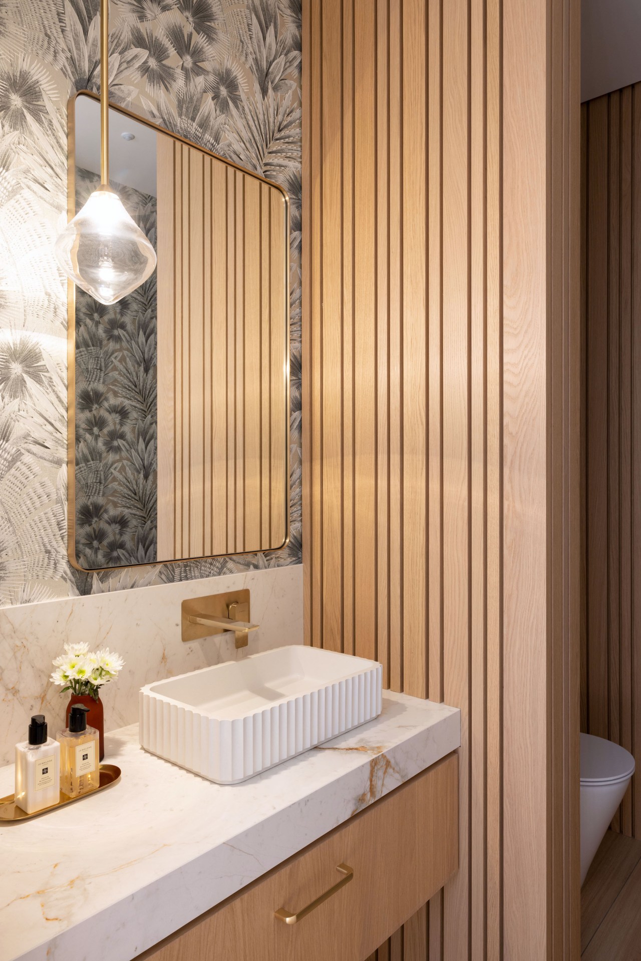 Powder room with wallpaper and feature slat-look joinery. 