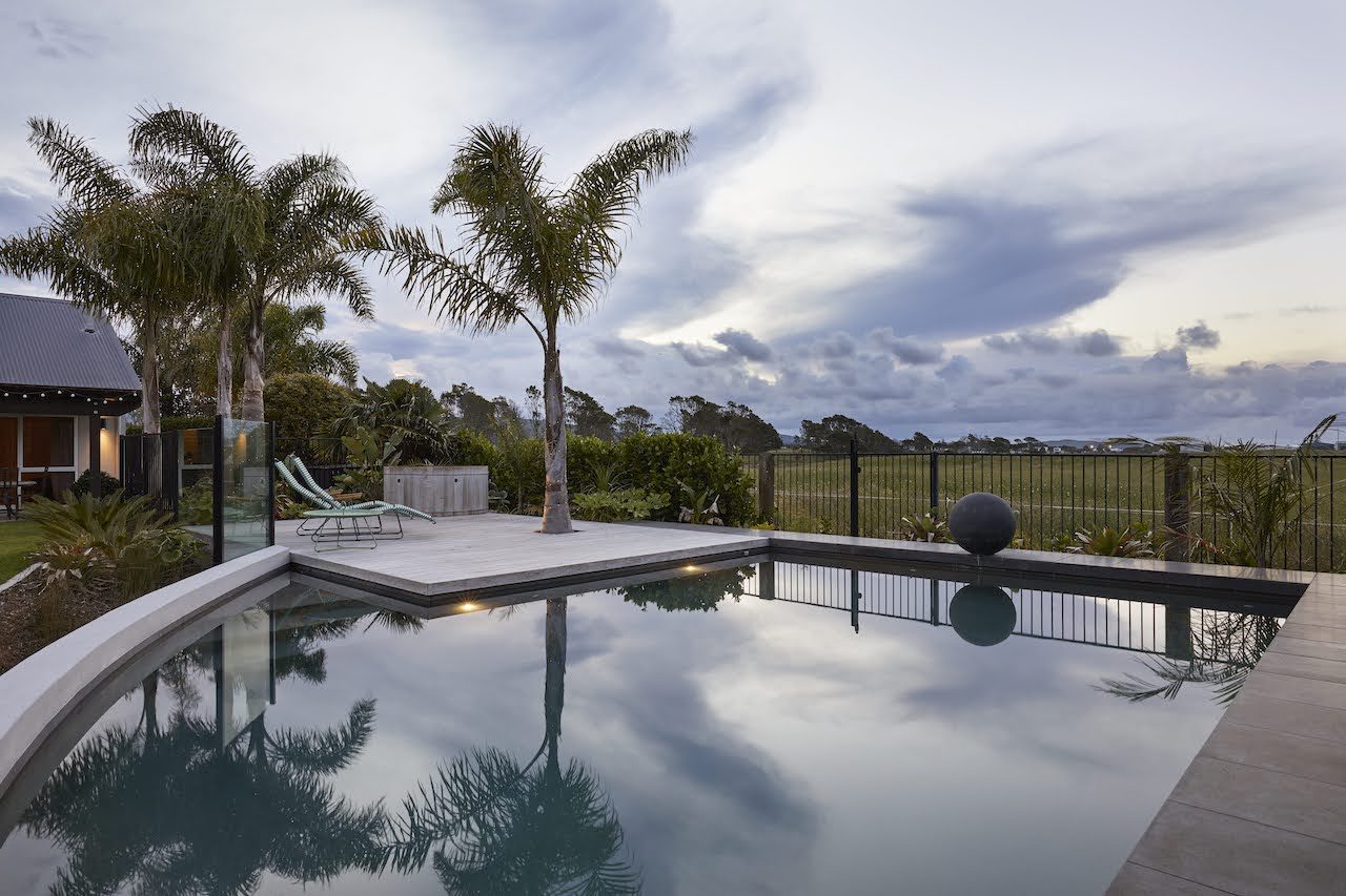 The corner swimming pool reflects the sky, palms 