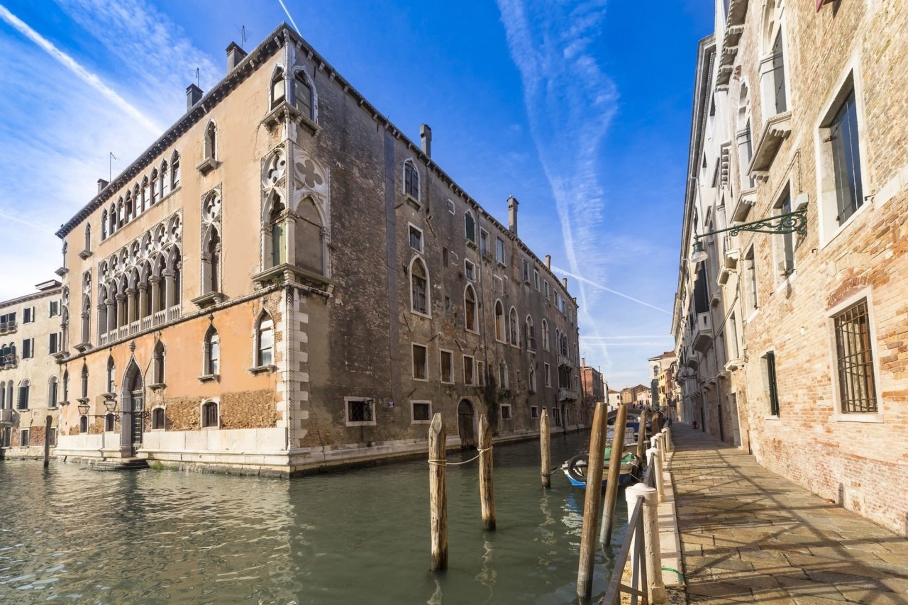 Located in the centre of the city, the building, canal, city, facade, historic site, medieval architecture, sky, tourist attraction, town, waterway, orange