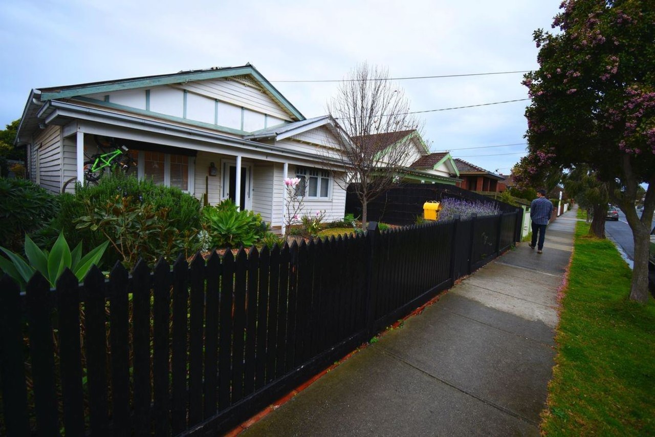 From the street, it's hard to imagine there's cottage, facade, fence, home, house, neighbourhood, plant, property, real estate, residential area, road, tree, walkway, black