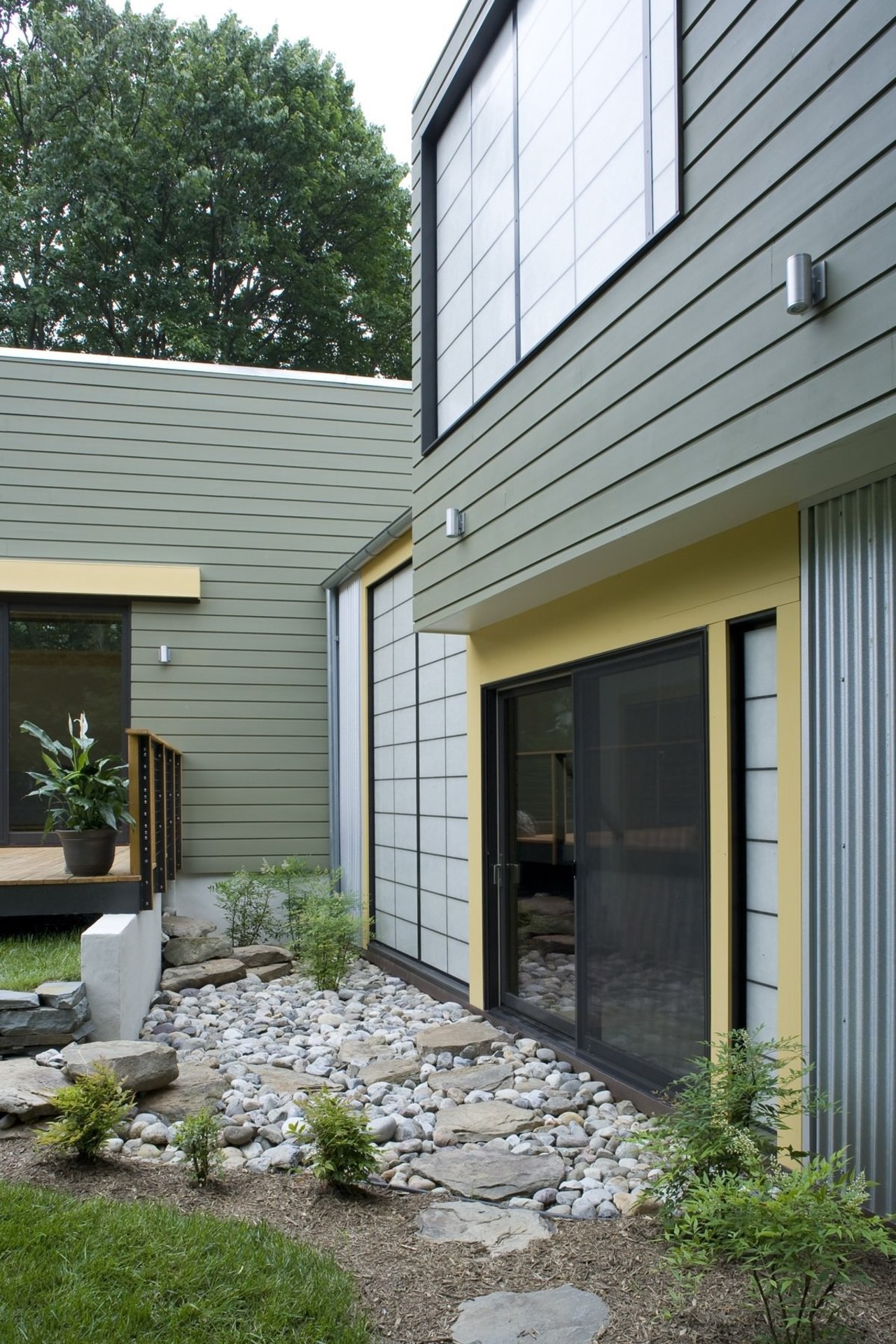 A rock garden sits outside this hallway backyard, cottage, courtyard, facade, home, house, real estate, residential area, siding, window, yard, gray