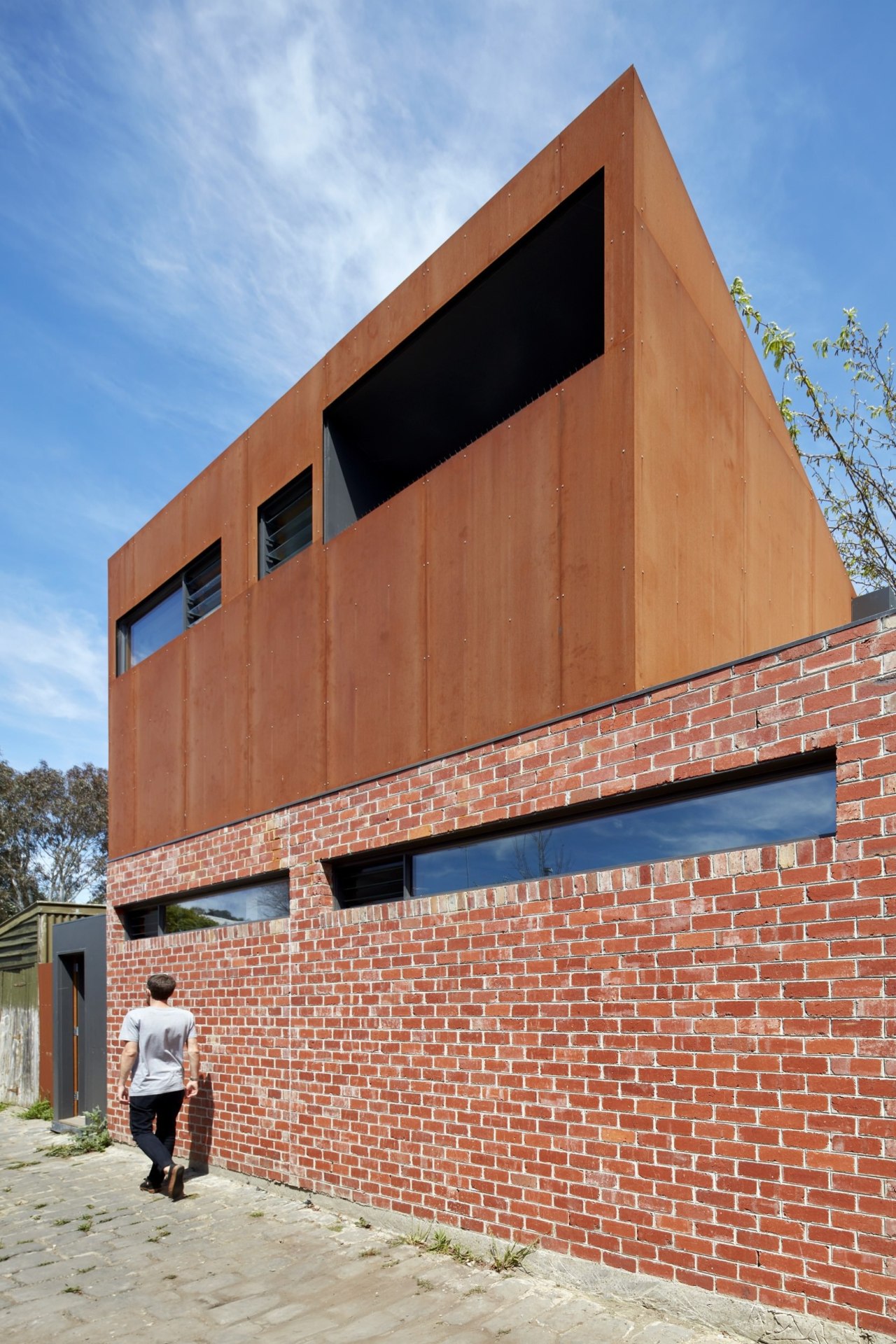 A Corten steel structure sits atop a brick architecture, brick, brickwork, building, commercial building, elevation, facade, house, real estate, residential area, siding, wall, red, teal