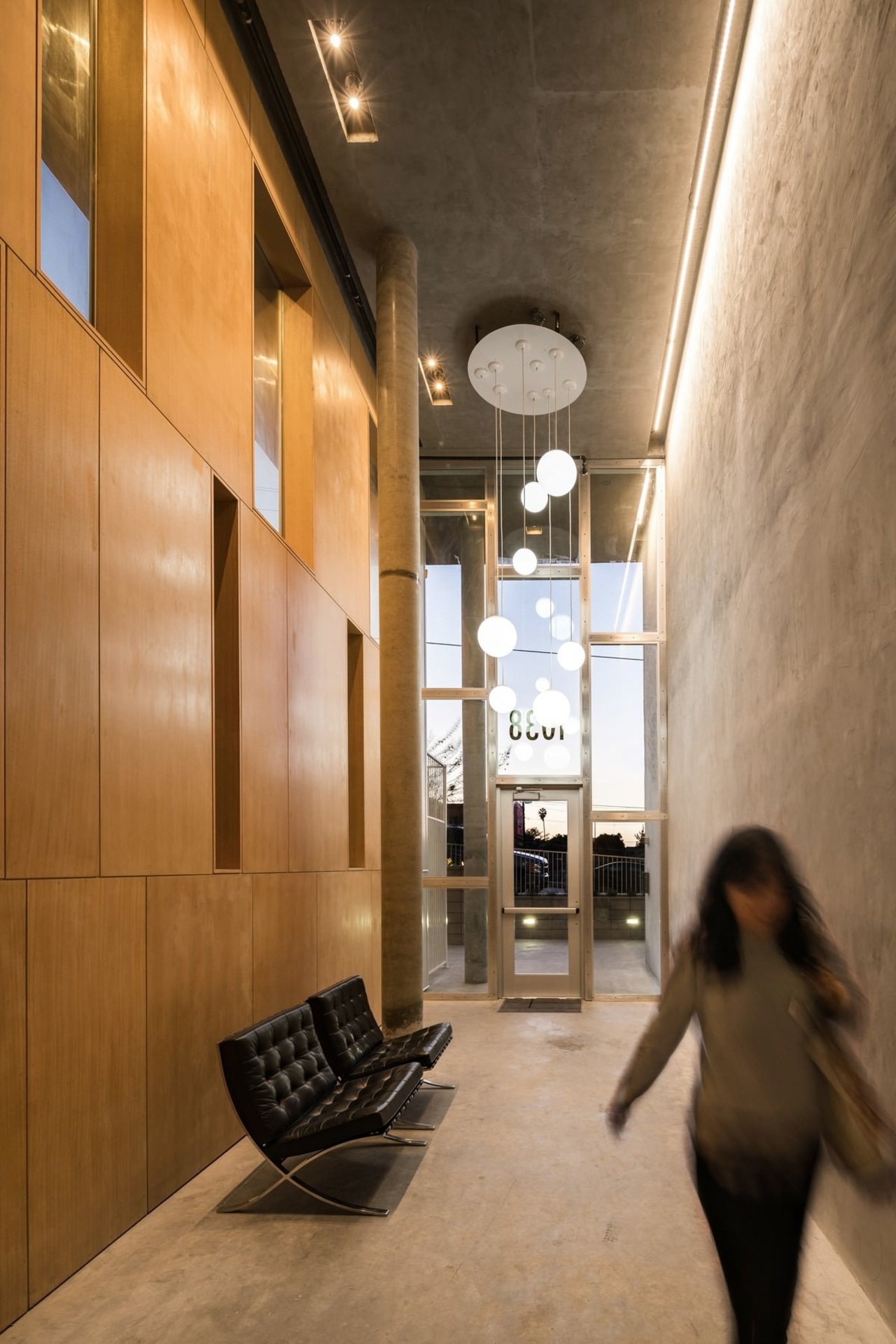 The entrance features contrasting concrete and wood architecture, ceiling, daylighting, floor, flooring, interior design, lobby, brown, orange