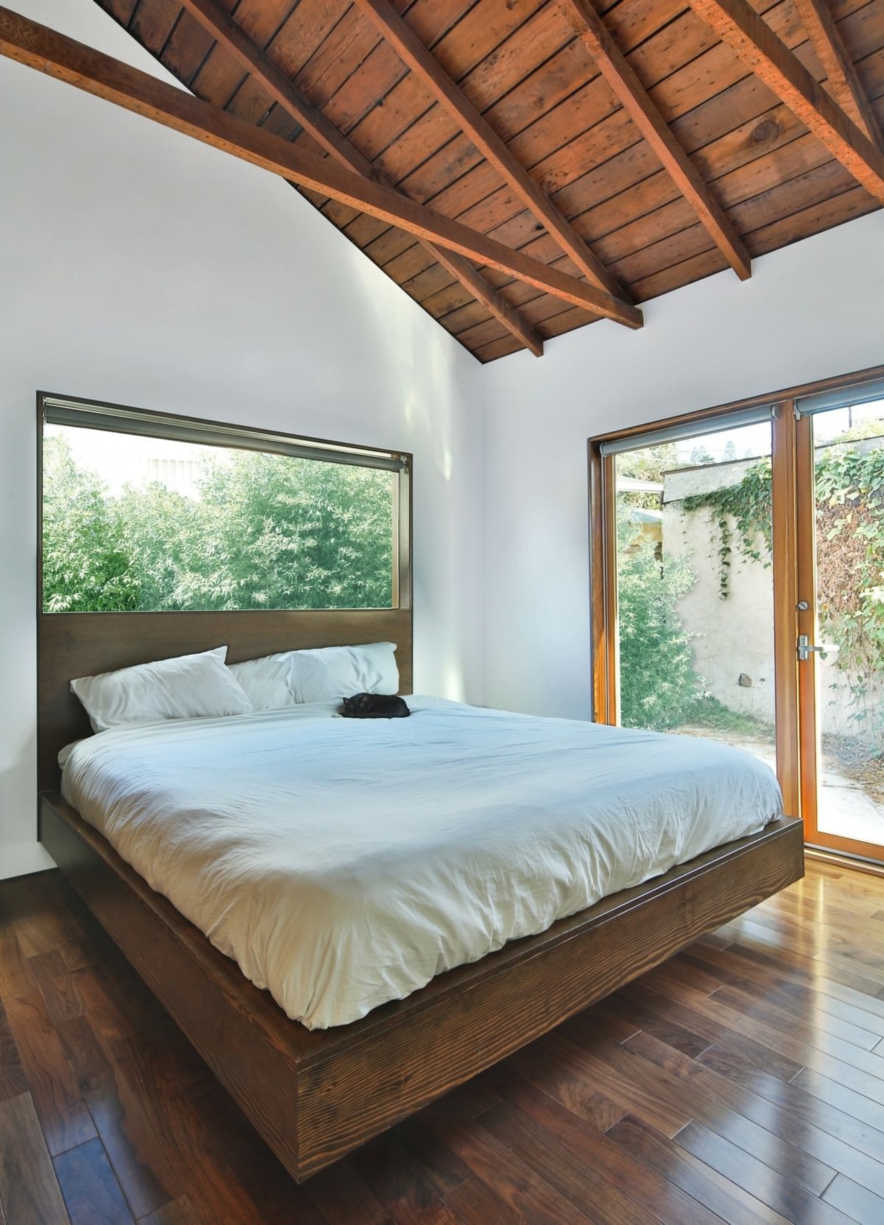 In the bedroom, plentiful use of glass and architecture, bed, bed frame, bedroom, ceiling, daylighting, estate, floor, hardwood, home, house, interior design, mattress, real estate, room, window, wood, wood flooring, gray, brown