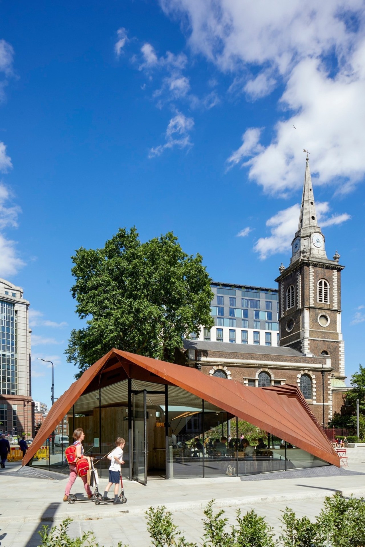 The structure sits within a new landscaped square building, landmark, plaza, sky, tree, teal