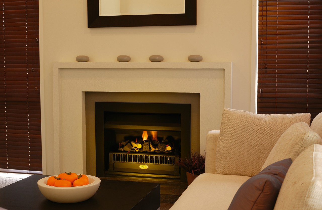 Fireplace with cream surround, ornaments on mantel and fireplace, hearth, interior design, living room, wood burning stove, brown, orange