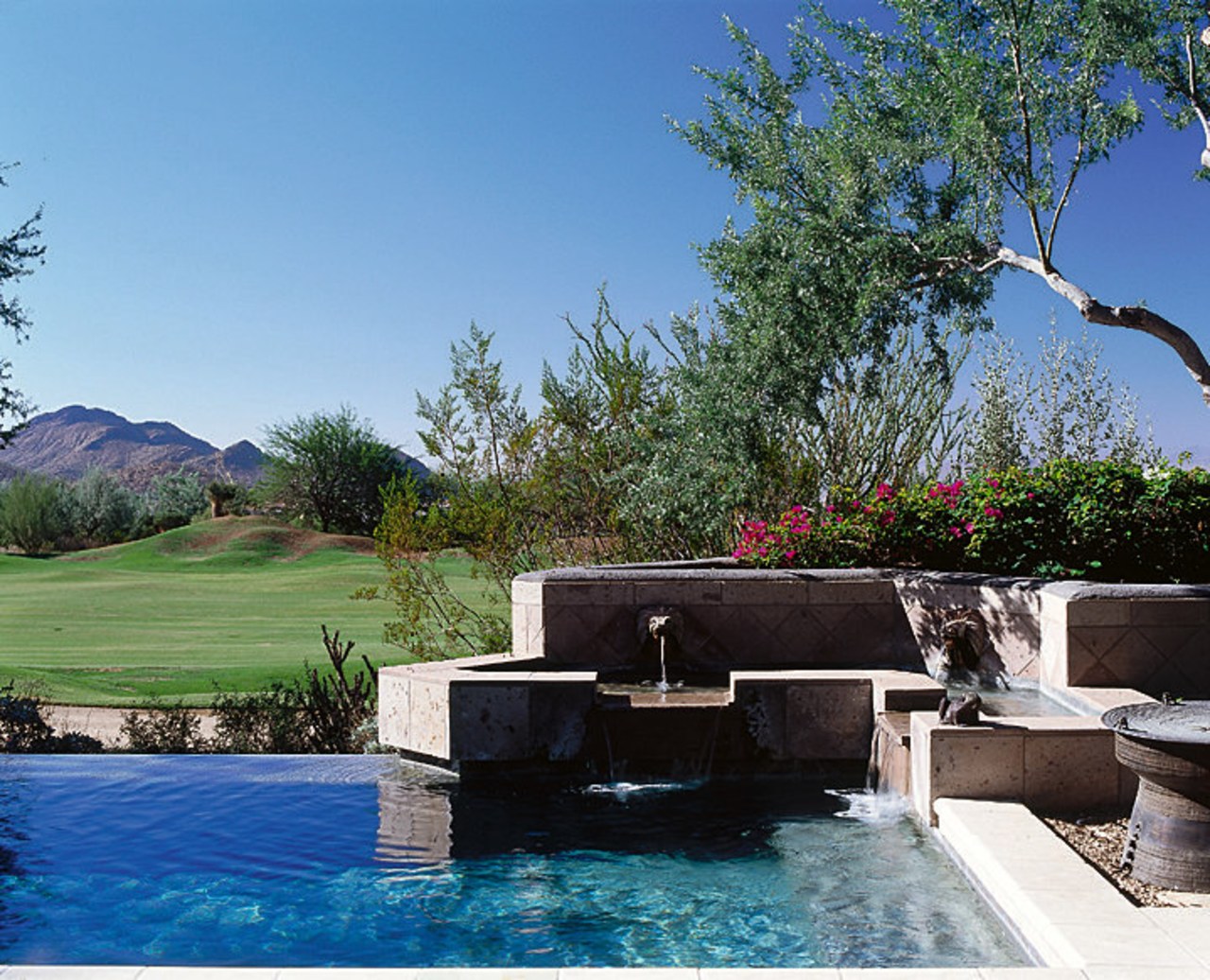 Close view of the water feature located beside backyard, estate, home, landscape, landscaping, leisure, plant, property, real estate, sky, swimming pool, tree, villa, water, water feature, teal