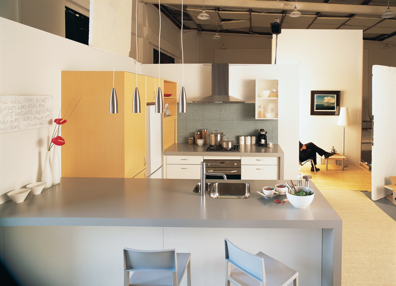 Showroom kitchen with blue grey benchtops, tan coloured exhibition, floor, flooring, furniture, interior design, loft, product design, table, white