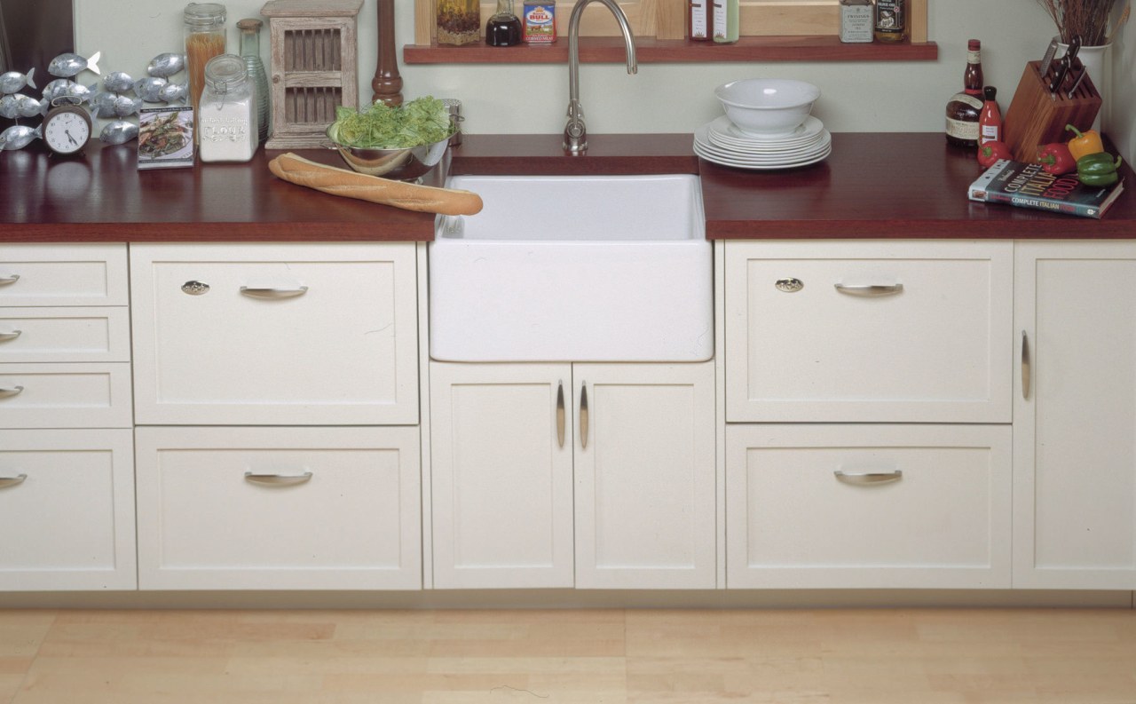 Kitchen with concealed appliances. Sink and faucetry between cabinetry, chest of drawers, countertop, cuisine classique, cupboard, drawer, filing cabinet, floor, furniture, hardwood, home appliance, kitchen, room, sideboard, wood stain, gray