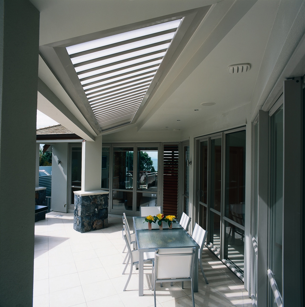 An outdoor sitting area featuring an aluminium opening ceiling, daylighting, interior design, real estate, roof, window, gray, black