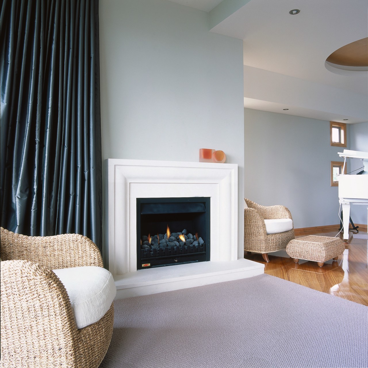 A small fireplace featuring a handcarved limestone surround ceiling, fireplace, floor, flooring, hearth, home, home appliance, interior design, living room, room, wall, wood burning stove, gray