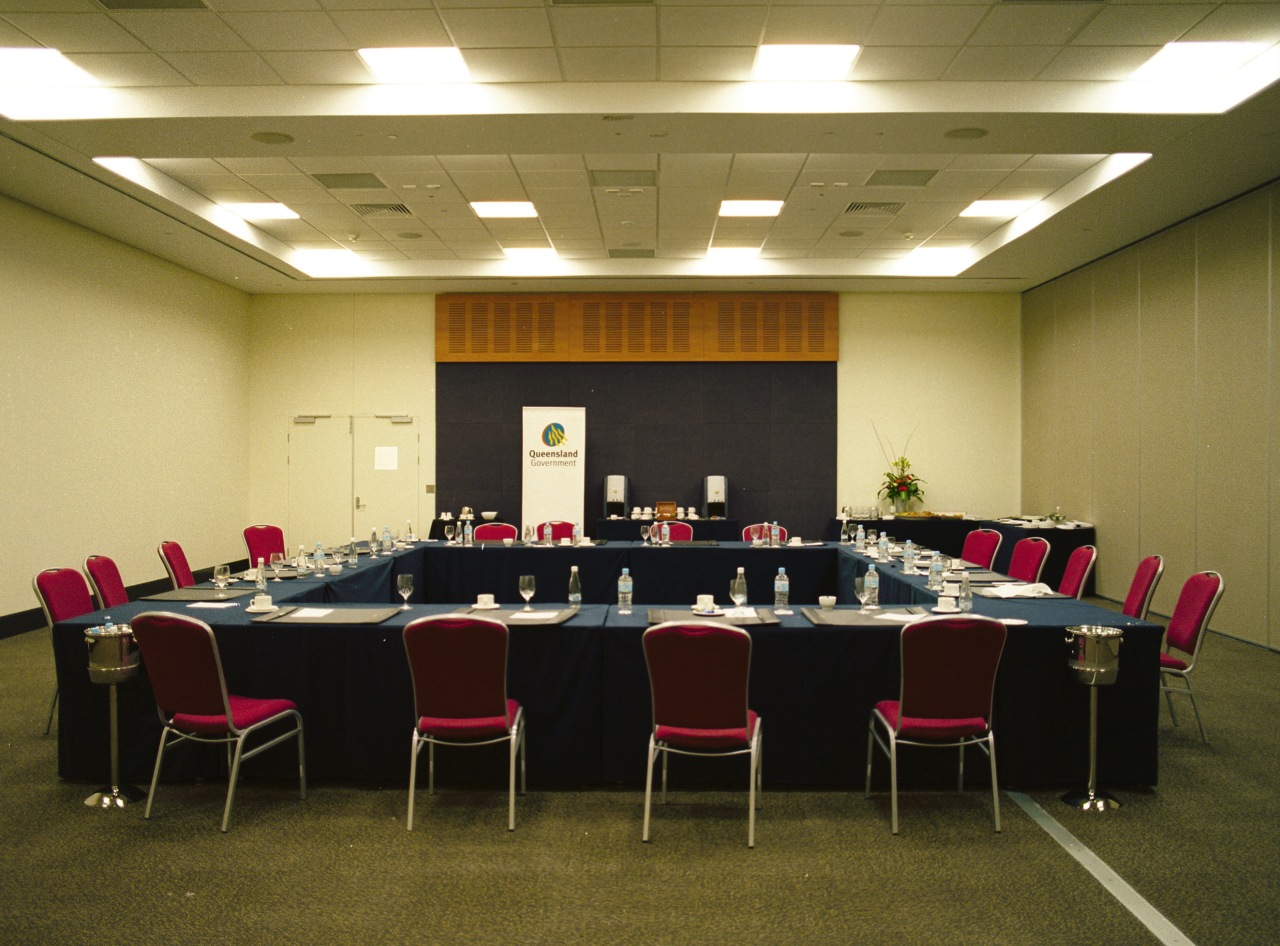 Meeting room with neutral coloured walls, square shaped conference hall, function hall, table, brown