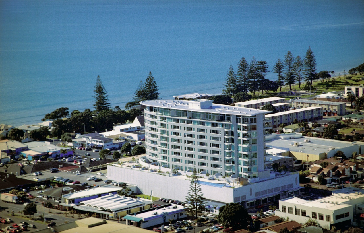 View of apartment building complex with beach behind. aerial photography, bird's eye view, city, condominium, hotel, mixed use, real estate, residential area, resort, sky, teal