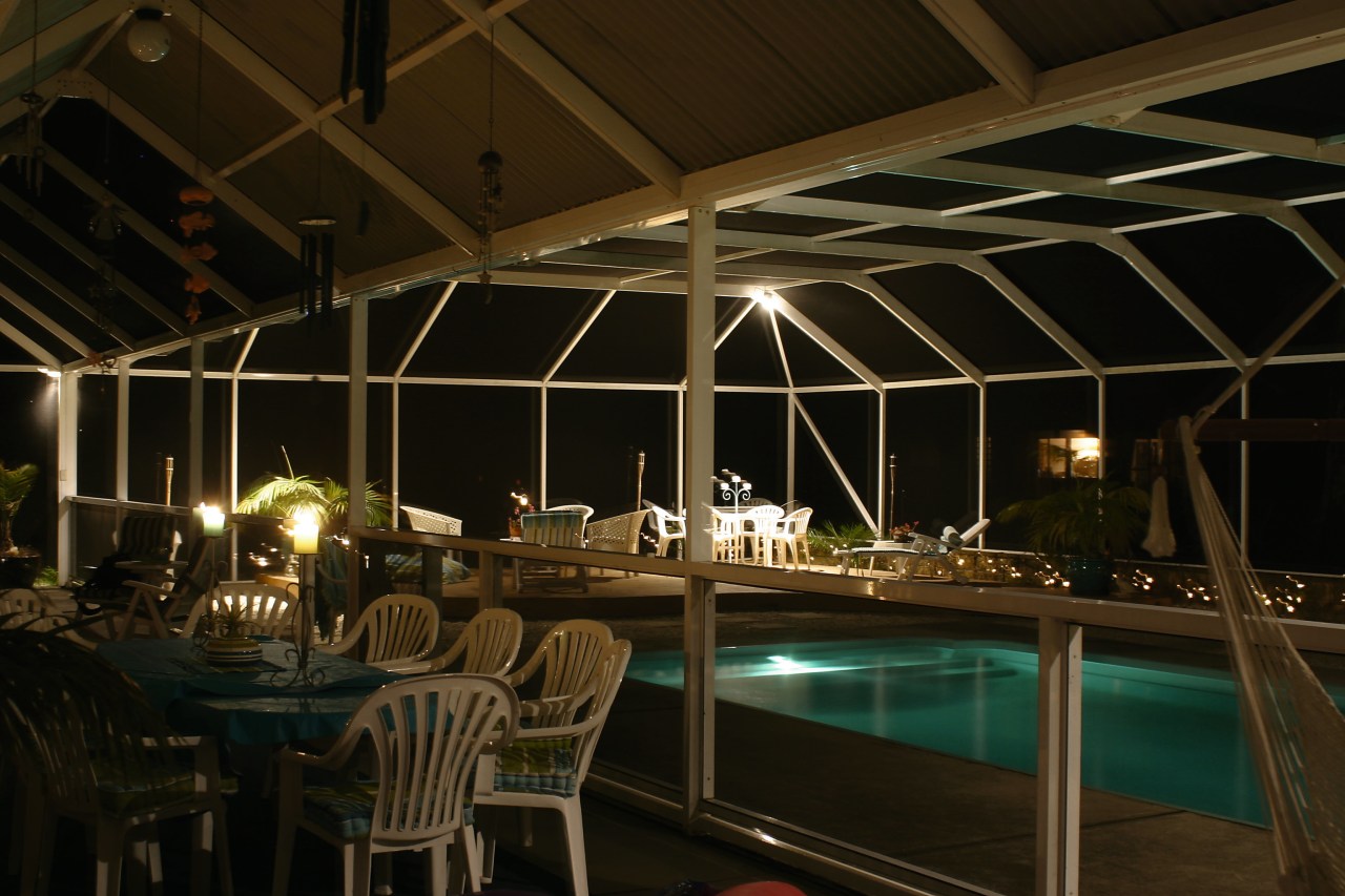 Eating area and pool area enclosed in glass lighting, night, black