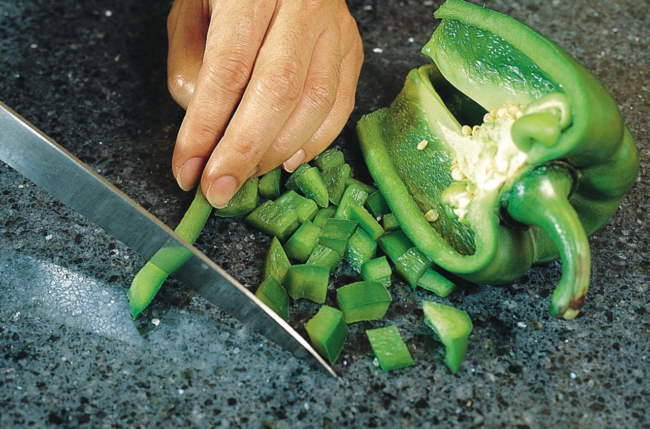 Closeup of granite benchtop with someone chopping vegetables. green, local food, vegetable, black, green