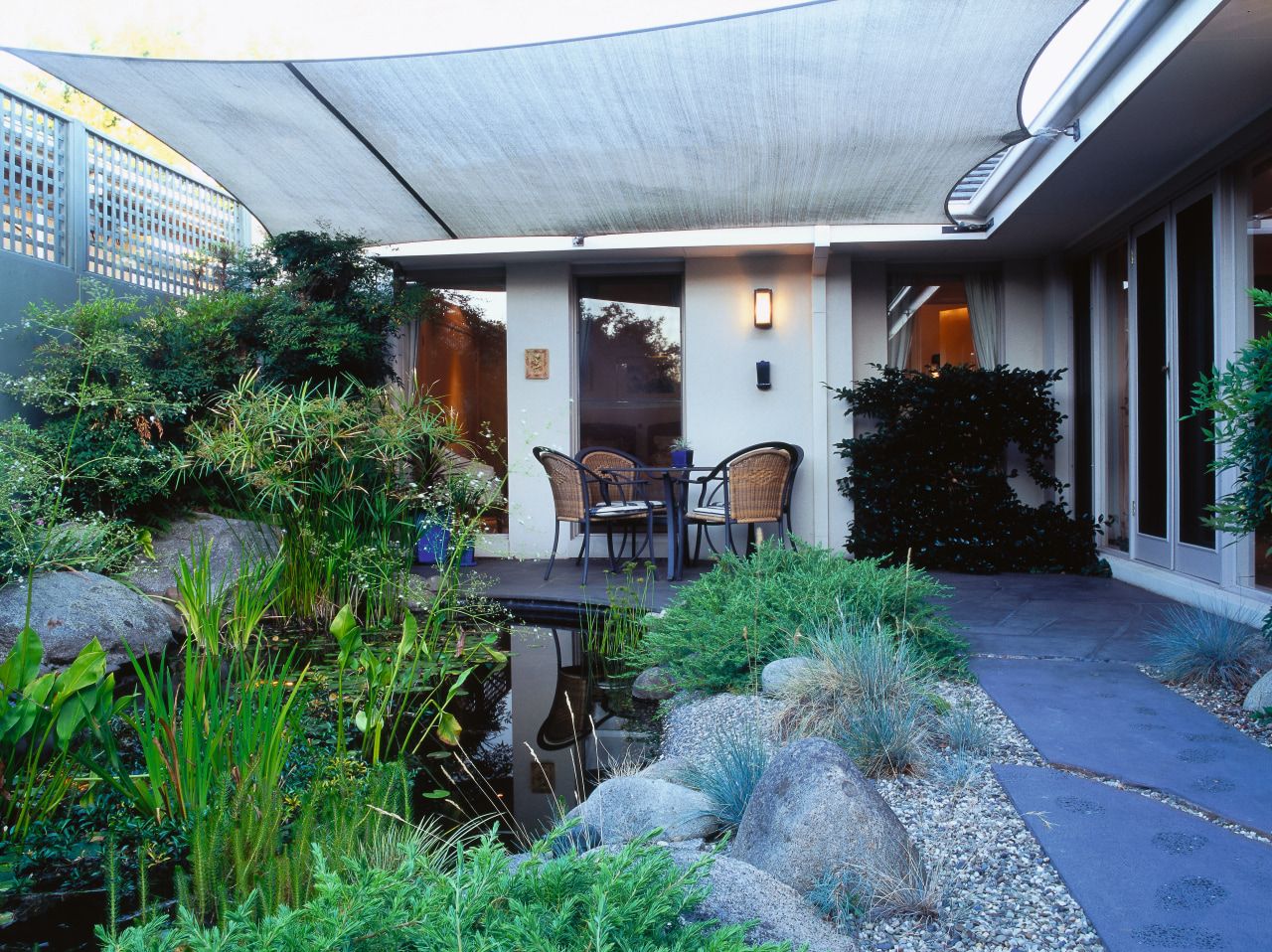 View of the patio area, concrete slab blocks backyard, cottage, courtyard, garden, home, house, landscaping, outdoor structure, patio, plant, property, real estate, roof, yard, white