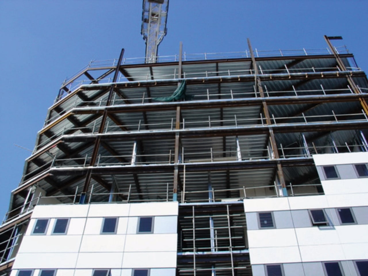 Exterior view of apartment building under construction. architecture, building, commercial building, condominium, construction, corporate headquarters, daytime, facade, headquarters, metropolis, metropolitan area, mixed use, residential area, scaffolding, sky, tower block, window, black, blue