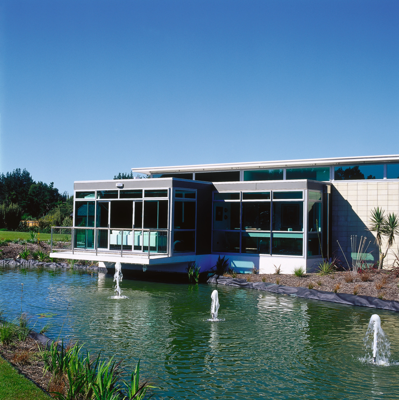 Exterior view of house with extensive glazing, grey architecture, home, house, leisure, property, real estate, sky, swimming pool, water, water transportation, waterway, teal