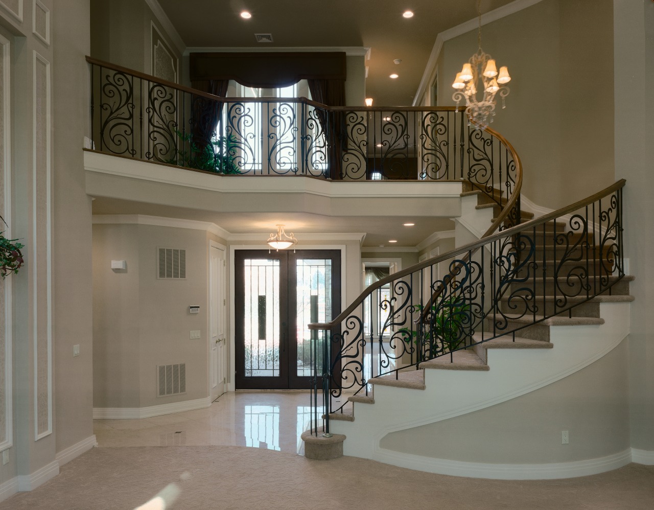 View of curved staircase in entranceway. baluster, ceiling, estate, floor, glass, handrail, home, interior design, iron, lobby, property, real estate, stairs, gray, brown