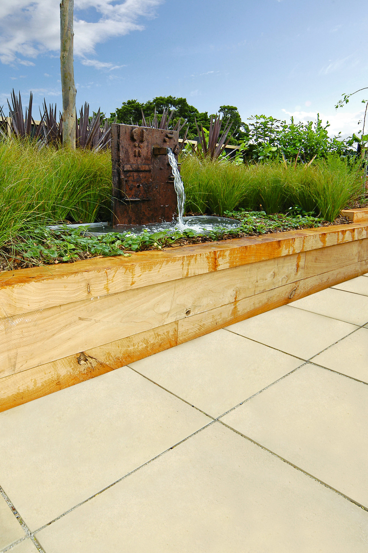 A view of some paving. backyard, grass, landscape, landscaping, outdoor structure, plant, walkway, wall, yard, yellow