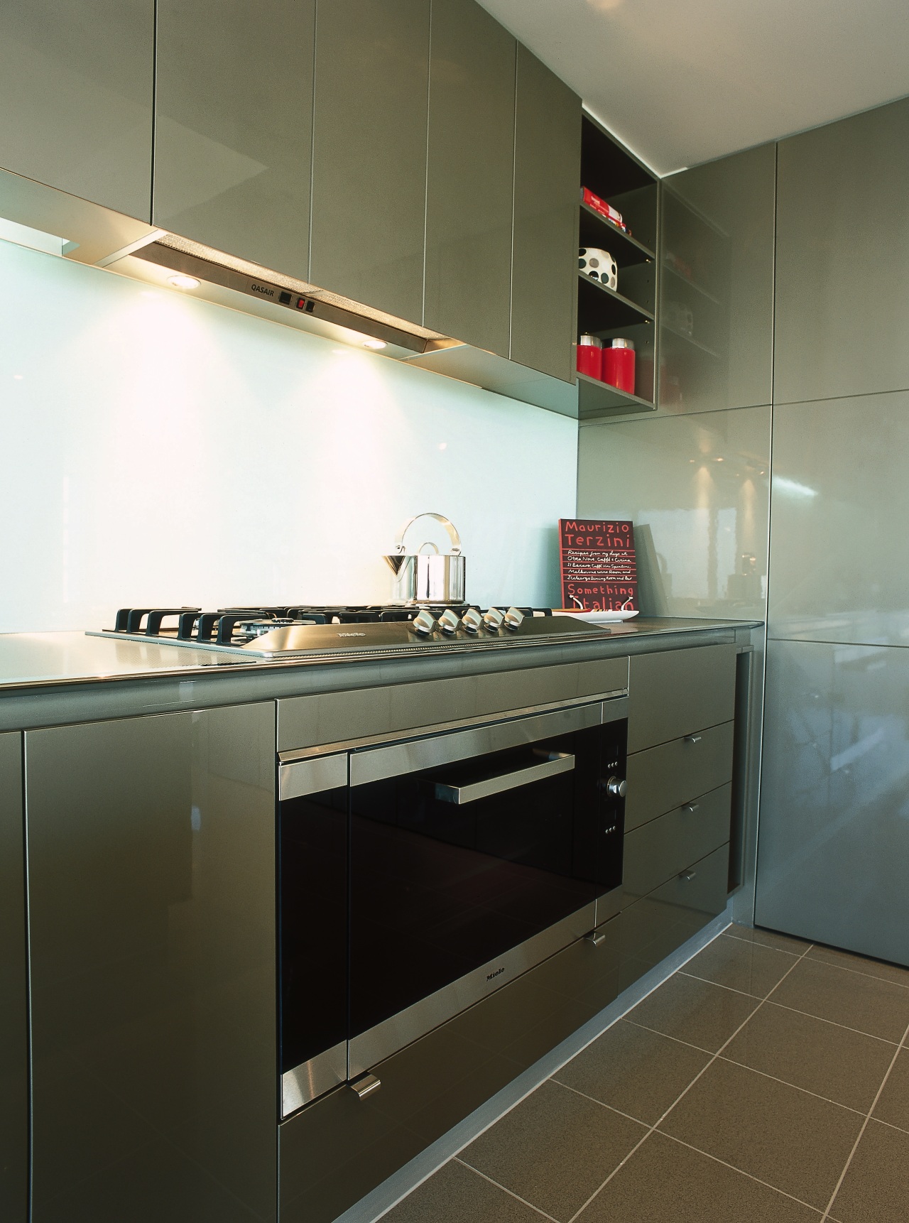 view of this kitchen featuring miele five burner architecture, cabinetry, countertop, floor, home appliance, interior design, kitchen, major appliance, room, sink, brown, black