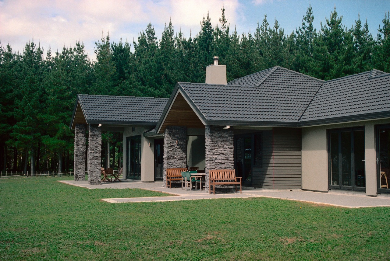 Exterior view of home with schist stone columns cottage, elevation, estate, facade, farmhouse, grass, home, house, landscape, outdoor structure, property, real estate, residential area, roof, siding, window, yard, green