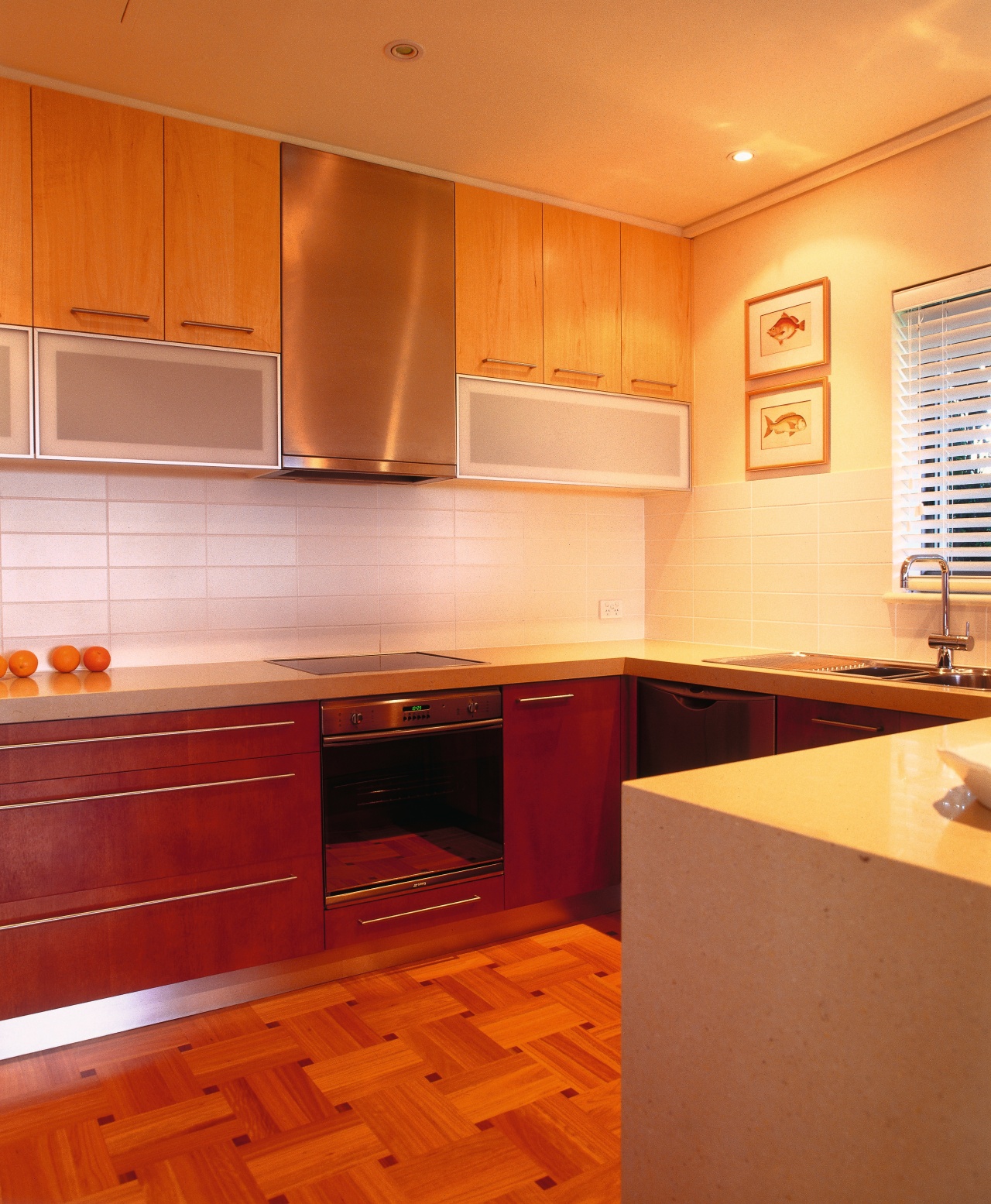 View of the kitchen featuring parquetry T&G flooring, cabinetry, ceiling, countertop, cuisine classique, floor, flooring, hardwood, home, interior design, kitchen, orange, real estate, room, tile, under cabinet lighting, wood, wood flooring, brown, orange